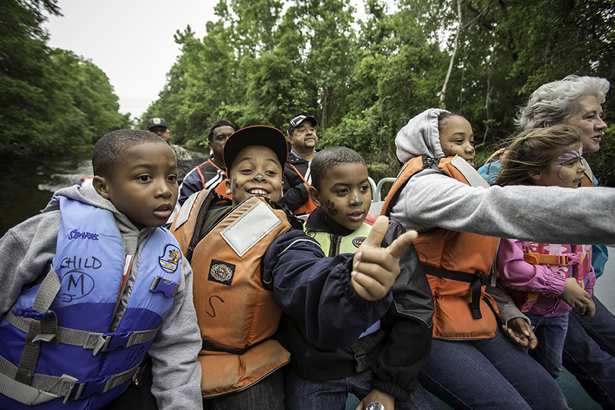 A group of children riding through the swamp in a boat
